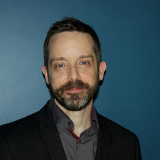 Photo of BrianHenry wearing a black jacket against a dark blue background